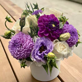 Bouquet of purple and white flowers in a white container