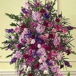 Tall standing spray of pink, purple, and lavender flowers in an elongated shape