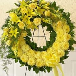 Yellow floral wreath with roses, lilies, and mums on a metal easel