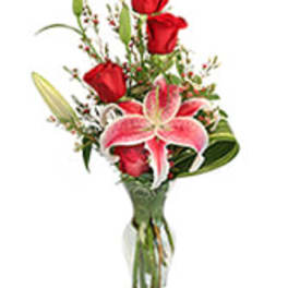 Bouquet of red roses and a pink lily in a clear glass vase