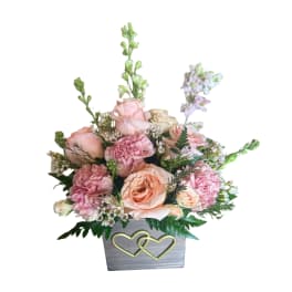 Pink and peach floral arrangement in a gray box with gold hearts