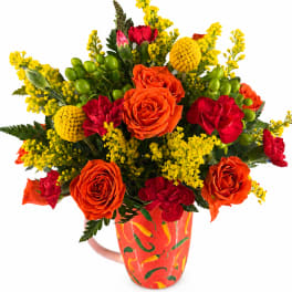 Bouquet of orange and red flowers in a painted mug vase