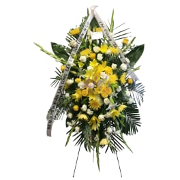 Yellow and white funeral standing spray with ribbon on an easel