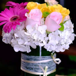 Mixed bouquet in a green vase with pink, yellow, and white flowers