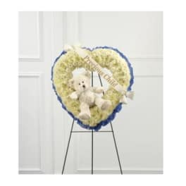 Heart-shaped white floral wreath with a teddy bear and ribbon on an easel