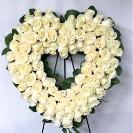 Heart-shaped wreath of white roses on a stand