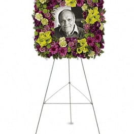 Floral funeral easel wreath framing a black-and-white portrait