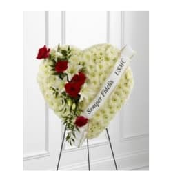 Heart-shaped white floral standing spray with red roses and a ribbon