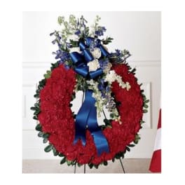 Red floral funeral wreath with blue ribbon and white accents
