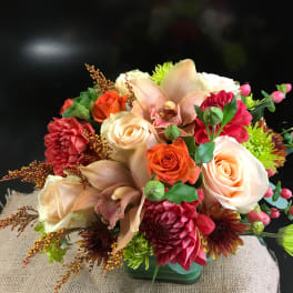 Mixed bouquet with roses, orchids, and chrysanthemums in a low container