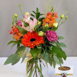 Mixed bouquet in a clear glass vase with orange, pink, and magenta flowers