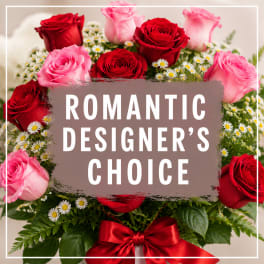 Red and pink roses with small white daisies in a bouquet with a red ribbon
