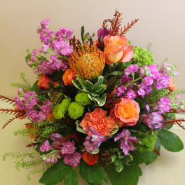 Mixed bouquet with orange roses, purple blooms, and green accents