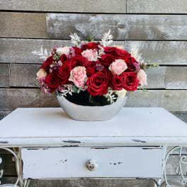 Red and pink roses arranged in a silver bowl vase