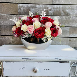 Red, pink, and white roses arranged in a silver bowl
