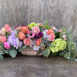 Low floral centerpiece with pink and coral roses in a copper vase