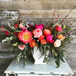Large mixed bouquet of pink, coral, and orange flowers in a white vase