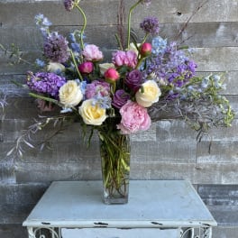 Tall mixed bouquet of pink, purple, and white flowers in a glass vase