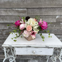 Mixed bouquet of pink, white, and peach flowers in a wooden cube vase