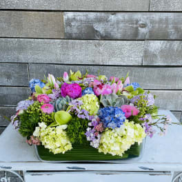 Colorful mixed flower arrangement in a rectangular glass vase