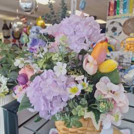 Basket of pastel artificial flowers with hydrangeas and tulips
