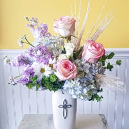 Pink roses and lavender flowers in a white vase