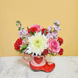 Pink and red flower arrangement in a heart-shaped mug and boot container