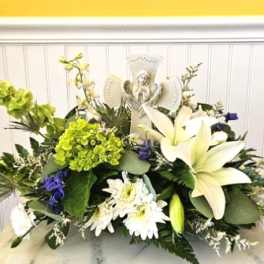 White lilies and daisies arranged around a religious figurine