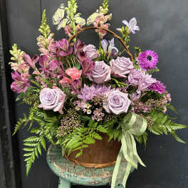 Basket arrangement of lavender roses and pink flowers with butterflies