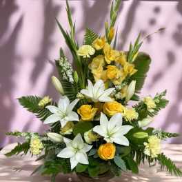 Yellow roses and white lilies arranged in a bronze vase