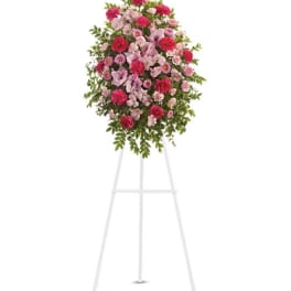 Standing floral spray of pink and red flowers on a white easel