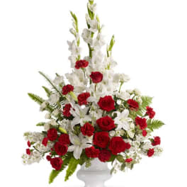 Tall red and white floral arrangement in a white pedestal vase