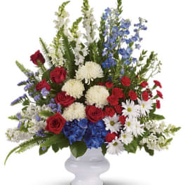 Mixed bouquet of red roses, white blooms, and blue flowers in a white vase