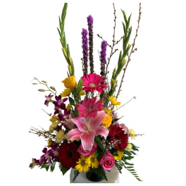 Tall mixed bouquet with pink lilies, gerberas, roses, and purple orchids in a vase