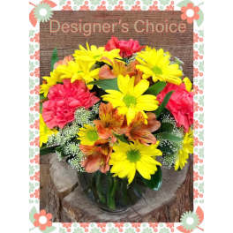 Mixed bouquet of yellow daisies, pink carnations, and orange alstroemeria in a glass vase