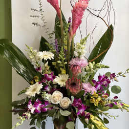 Tall mixed floral arrangement with pink tropical blooms and orchids in a vase