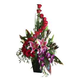 Tall arrangement of red roses and pink lilies in a black vase