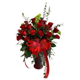 Red roses and carnations in a red vase with a large red ribbon