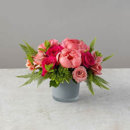 Pink and coral flowers arranged in a gray vase