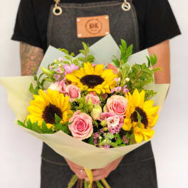 Bouquet of sunflowers and pink roses wrapped in pale paper