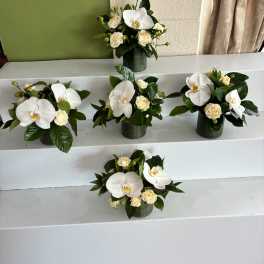 White orchid and cream rose arrangements in green containers