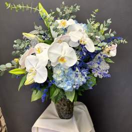White orchids and blue hydrangeas in a glass vase