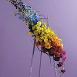 Tall multicolored floral arrangement on a stand against a purple background