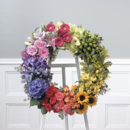 Colorful floral wreath on a stand with roses, lilies, sunflowers, and hydrangeas