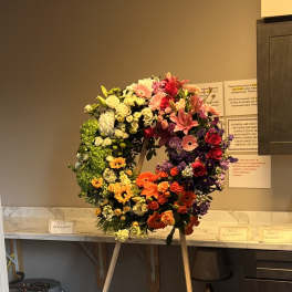 Large circular floral wreath on an easel with mixed roses and lilies