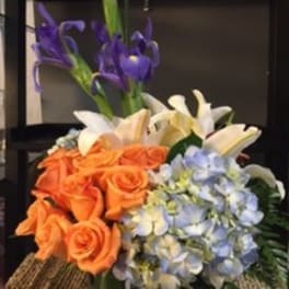 Bouquet of orange roses, blue hydrangeas, white lilies, and purple irises