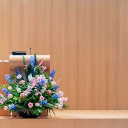 Large mixed floral arrangement in pink, blue, and white on a stage podium