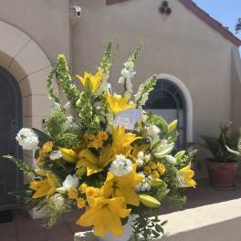 Large yellow lily and white floral arrangement in a white vase