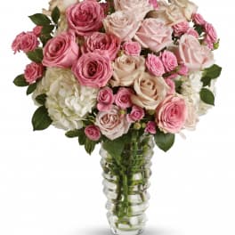 Tall vase arrangement of pink and ivory roses with white hydrangeas in a clear glass vase