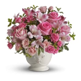 Pink and blush roses with pink alstroemeria arranged in a white ceramic urn.